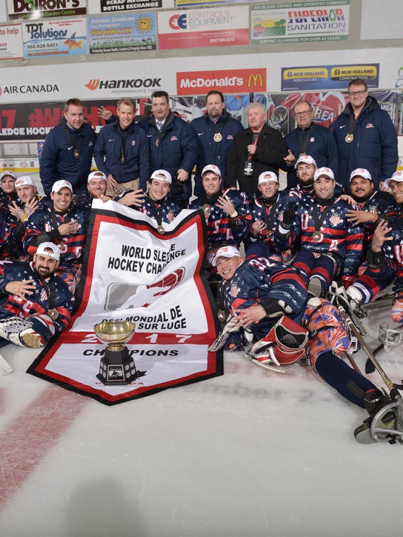 A group of Para ice hockey players pose with their trophy on the ice