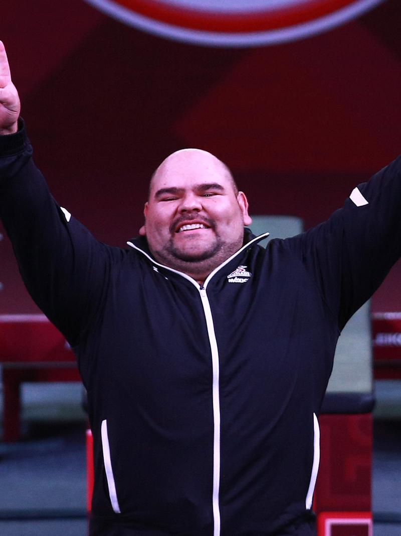 a male powerlifter raises his arms in celebration