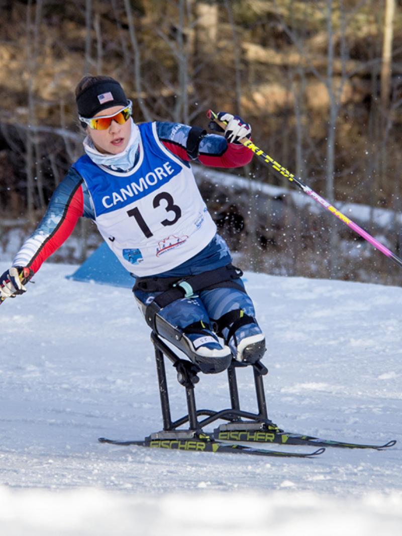 a female Para Nordic skier races towards the finish line