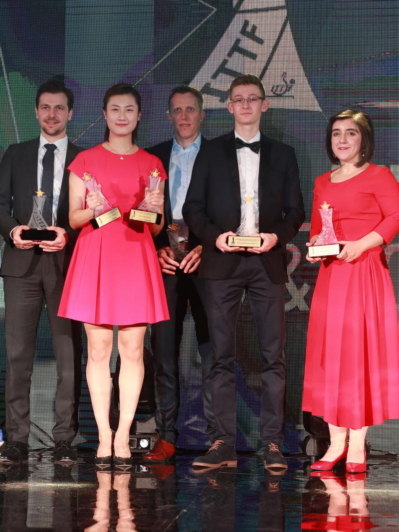 a group of men and women stand on stage with their trophies