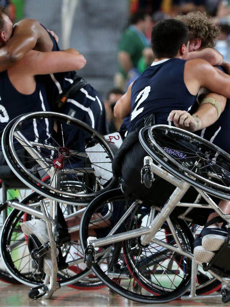 male wheelchair basketball players hug eachother on the court
