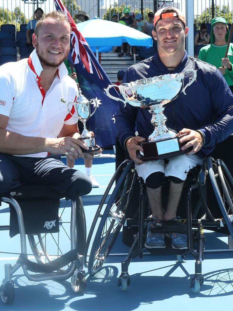 two male wheelchair tennis players hold up their trophies