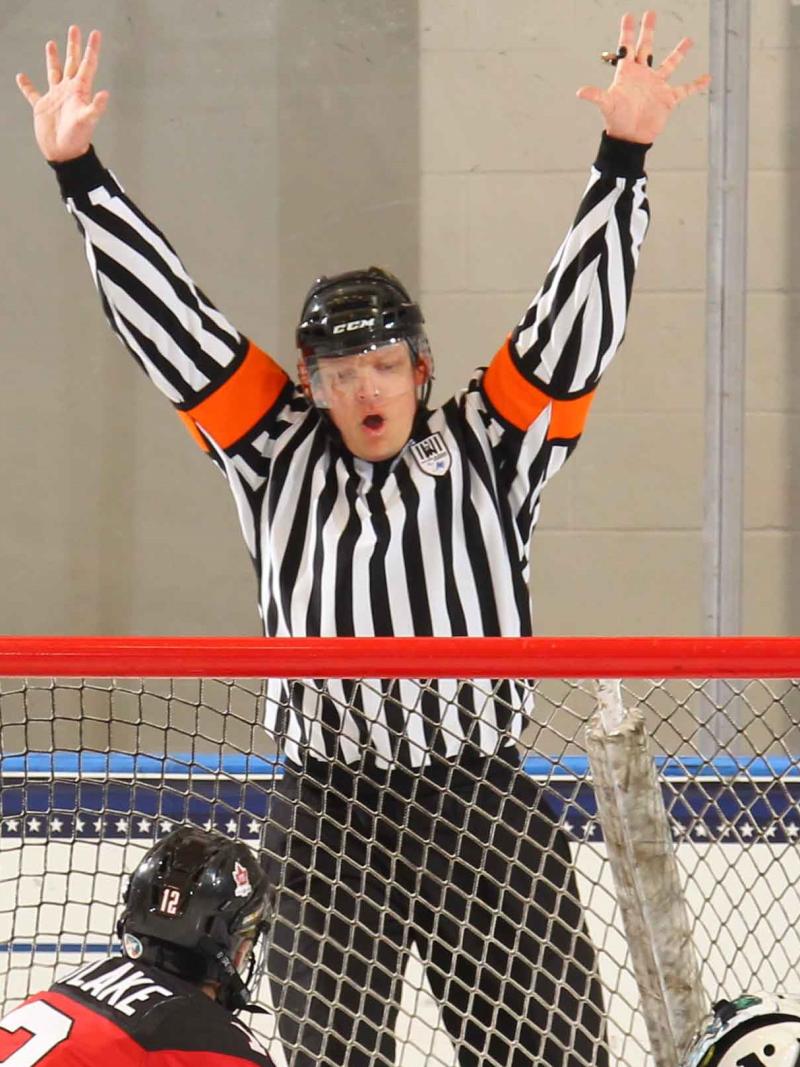 a male Para ice hockey referee throws his hands up to signal