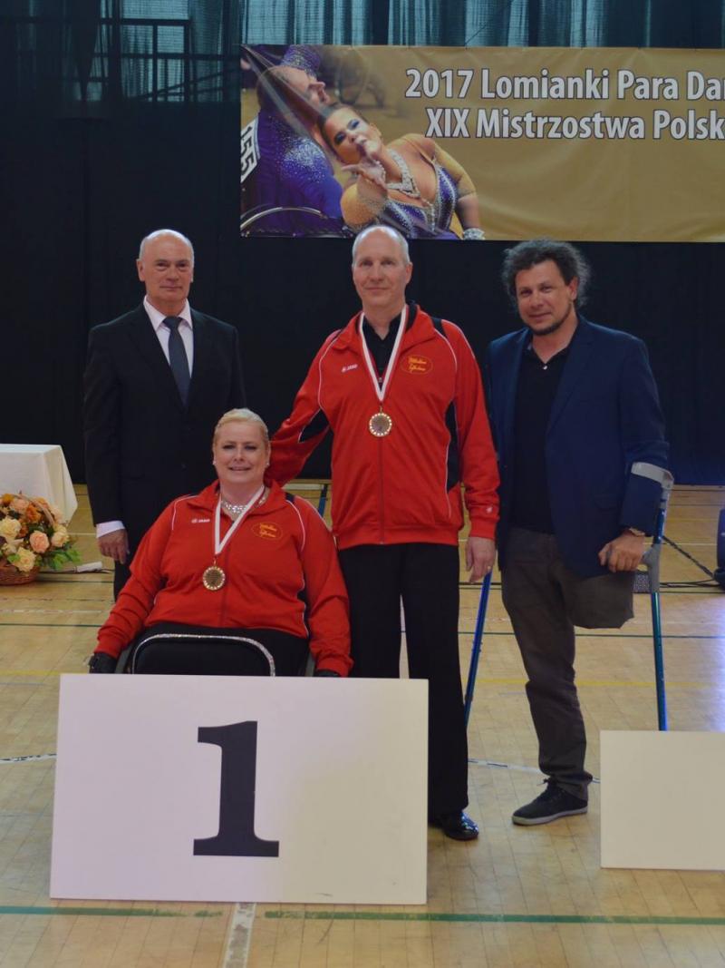 Female dancer in wheelchair poses for photo with standing partner and two other officials