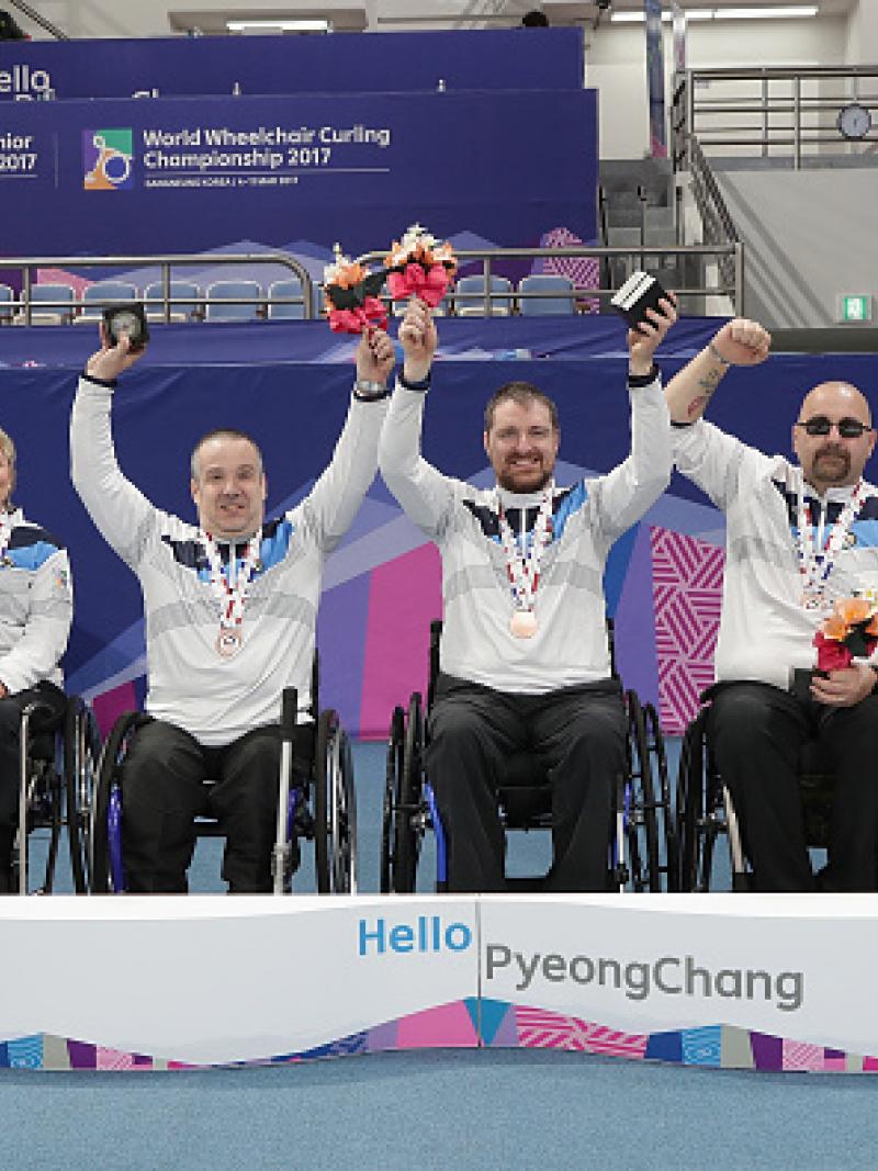 a group of wheelchair curlers celebrate with their medals