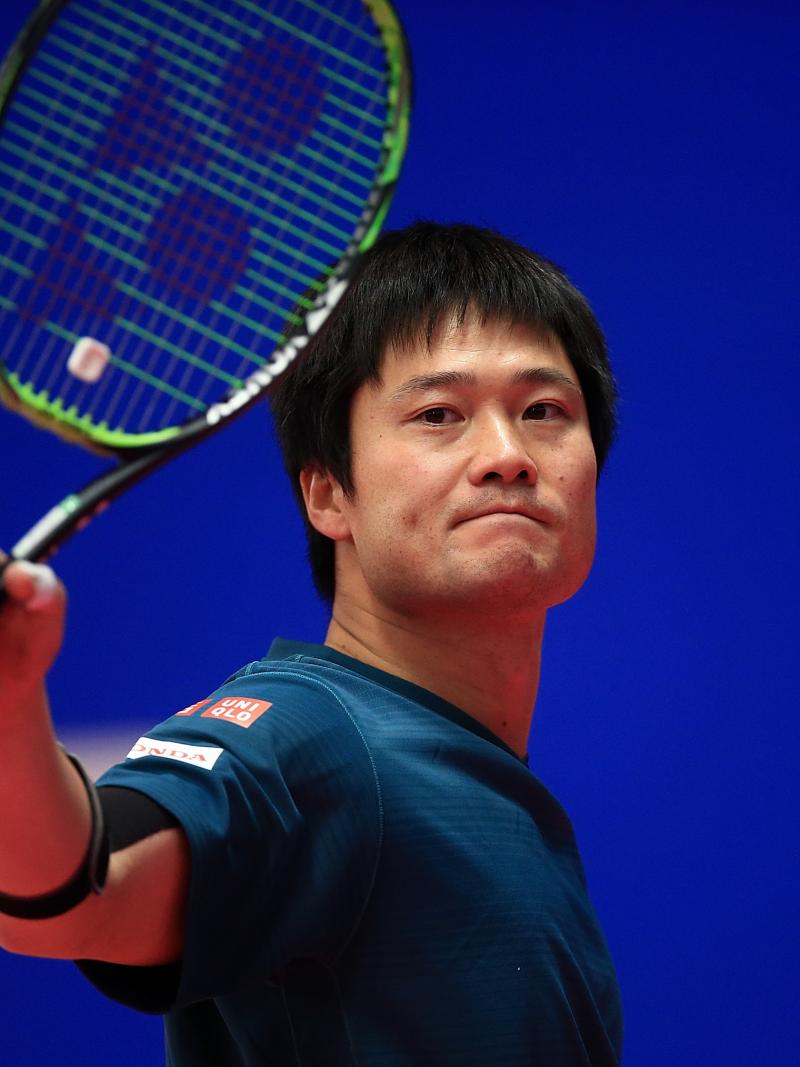 a male wheelchair tennis player holds up his racket 