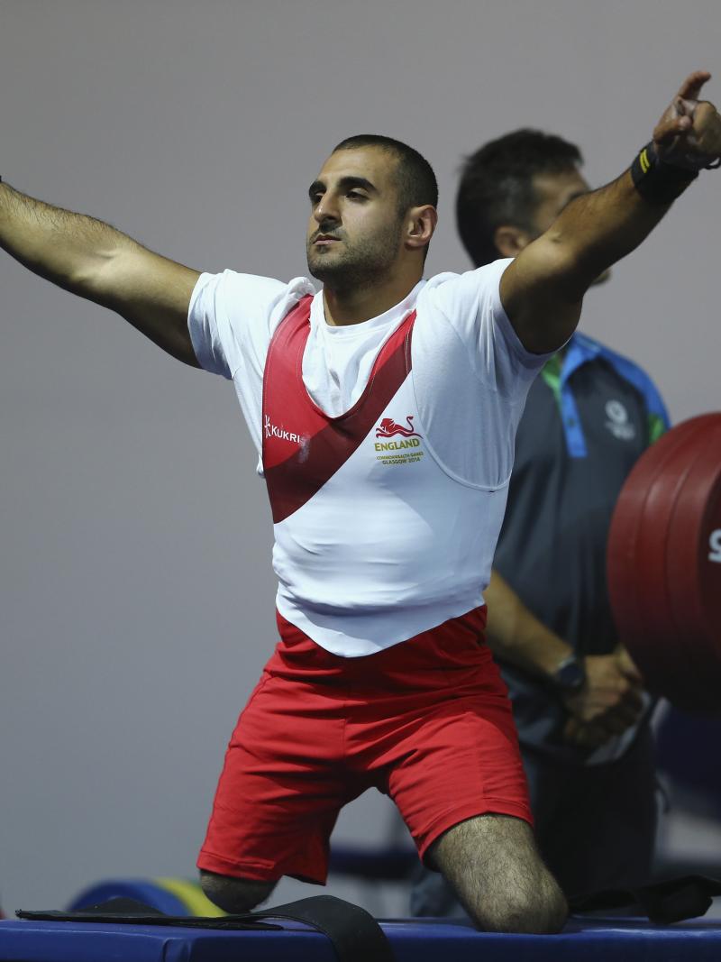 a male powerlifter raises his arms in celebration on the bench
