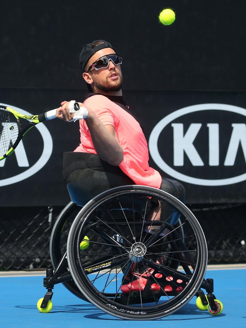 a male quad tennis player takes a shot