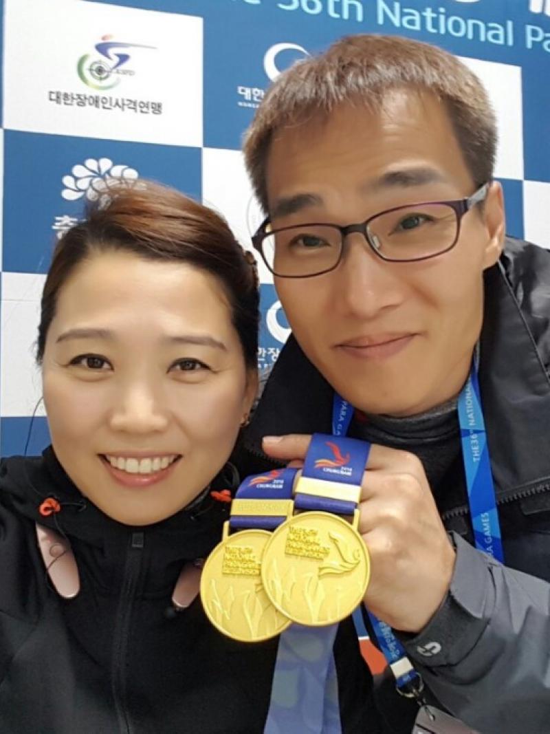 a man and a woman hold up a medal