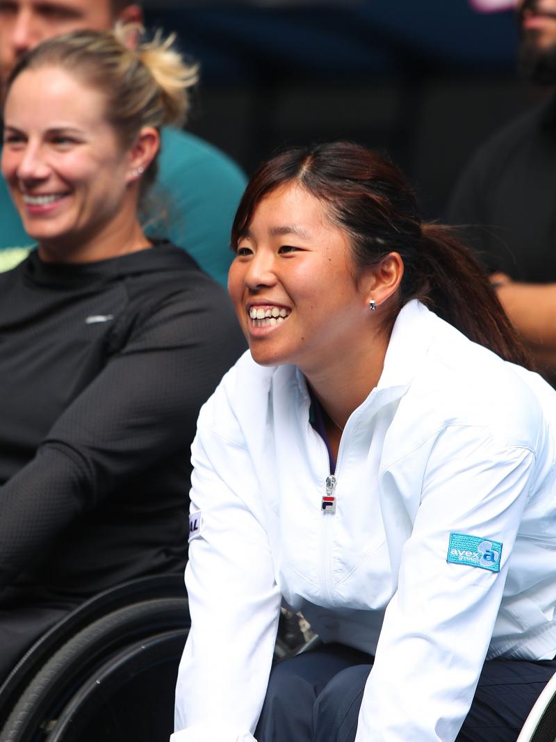 a female wheelchair tennis player smiles in delight