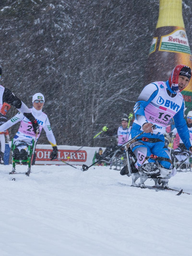 a group of male sit skiers race on the snow