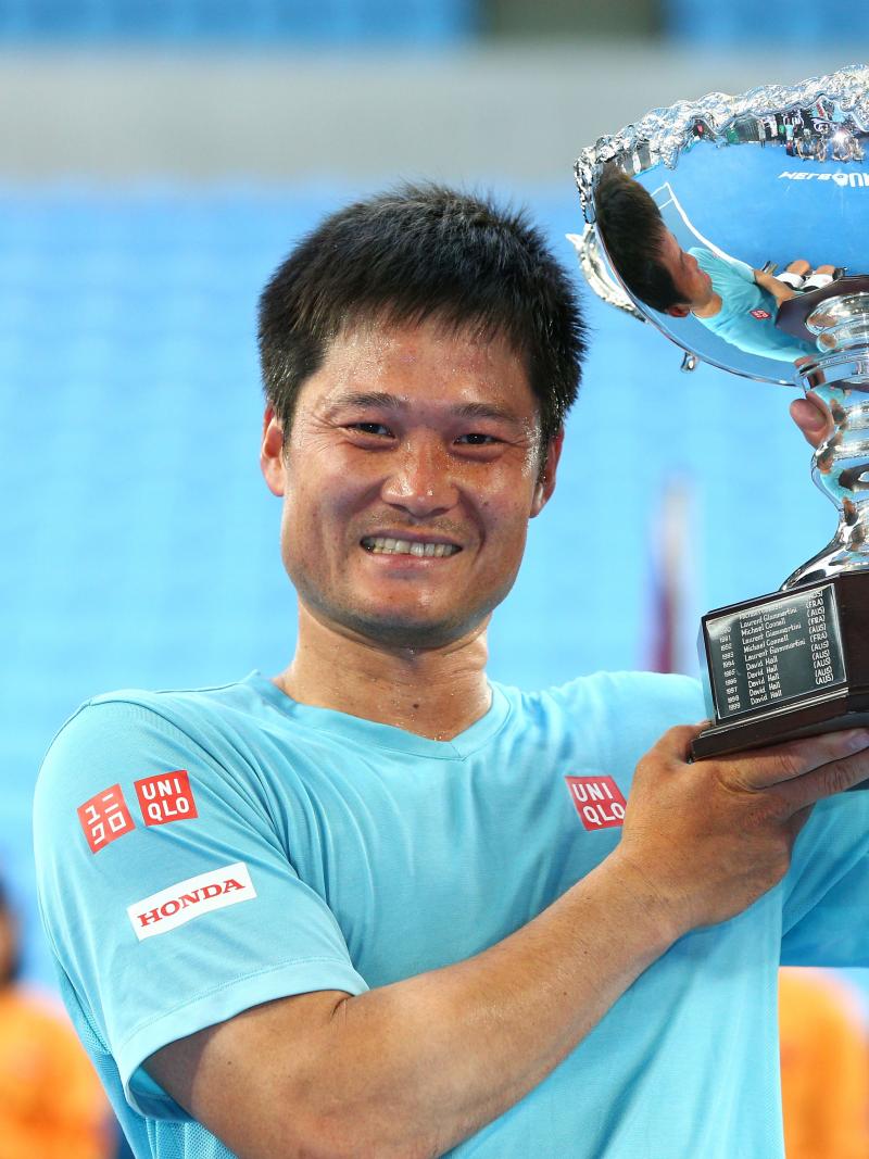 Man smiling and lifting a silver trophy