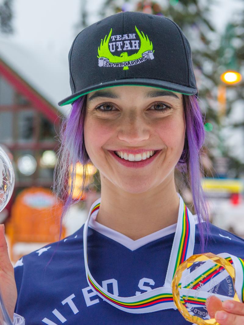 a female snowboarder holds up a crystal globe and medal