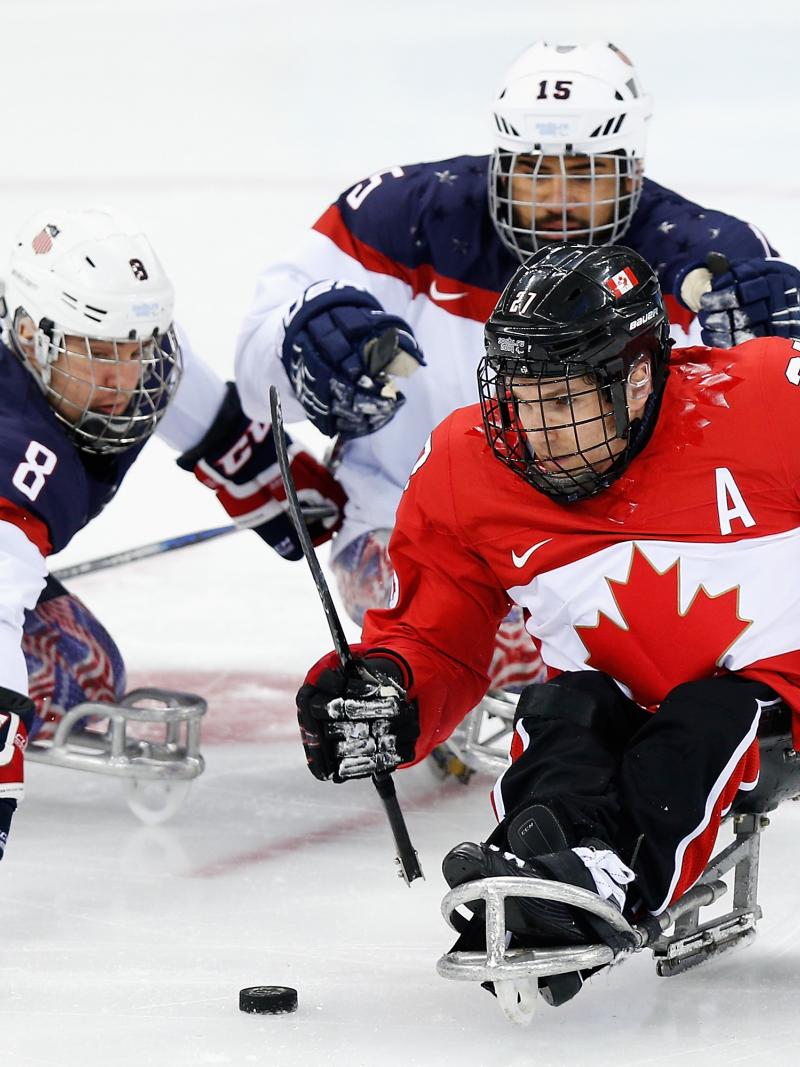 three male Para ice hockey players clash on the ice