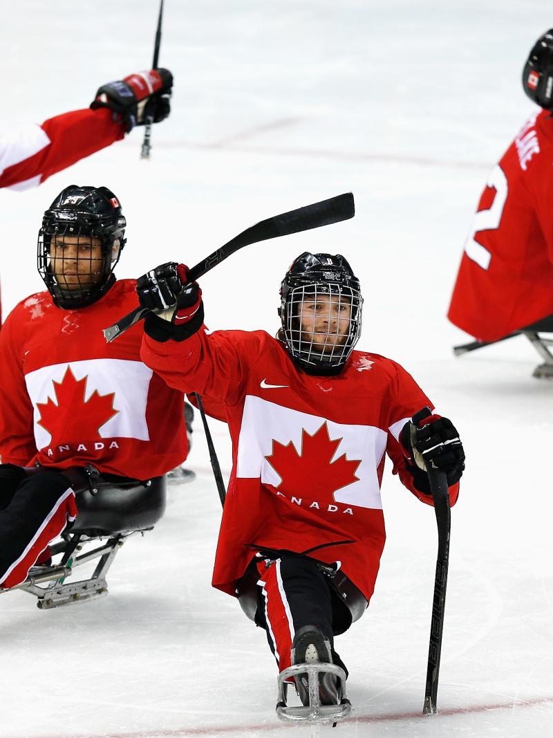 four male Para ice hockey players celebrate on the ice
