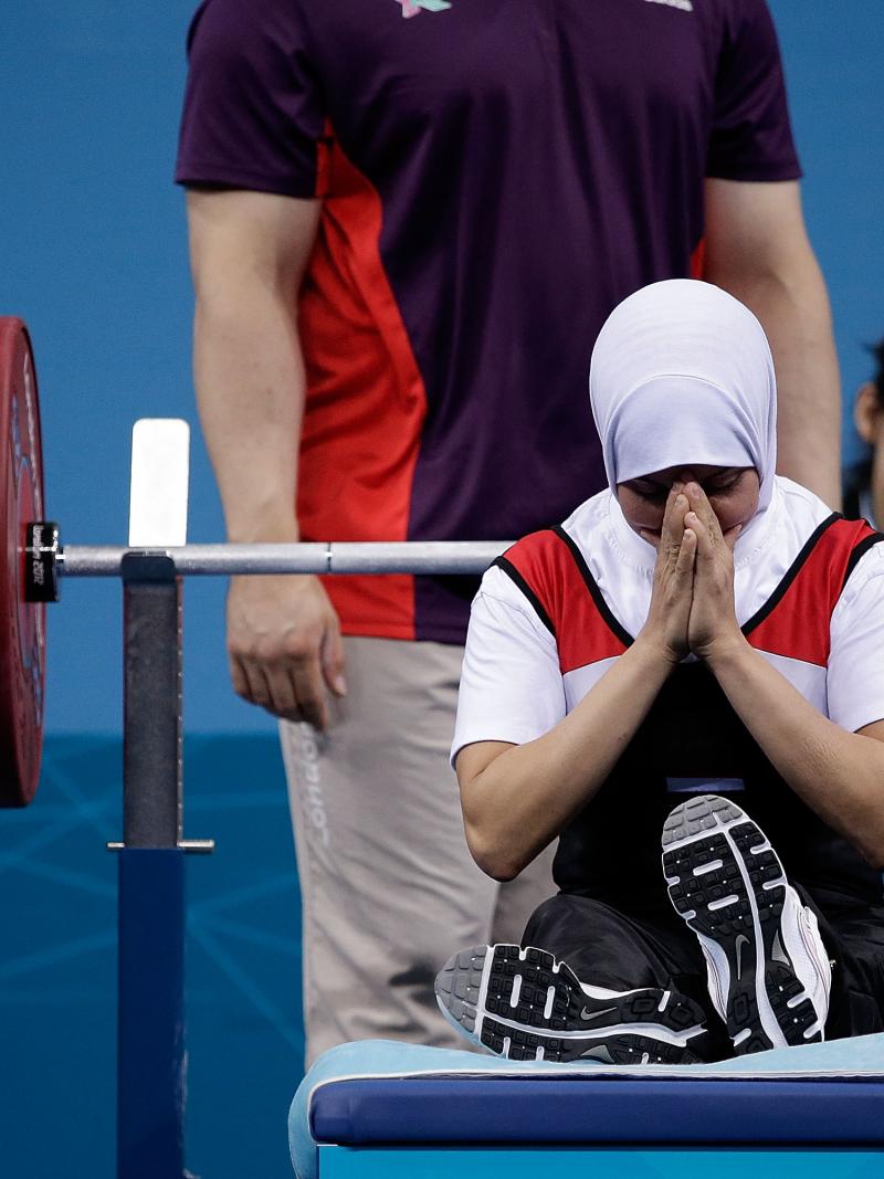 A female powerlifter prays on the bench before a lift
