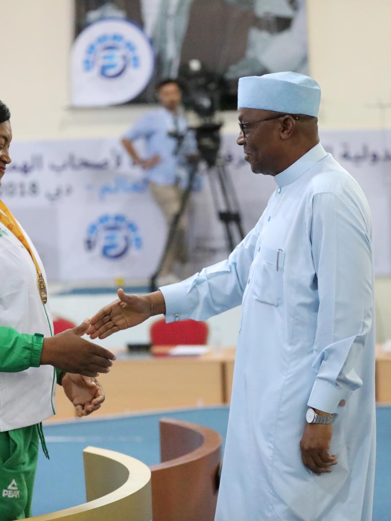 a female powerlifter shakes hands with a sheikh