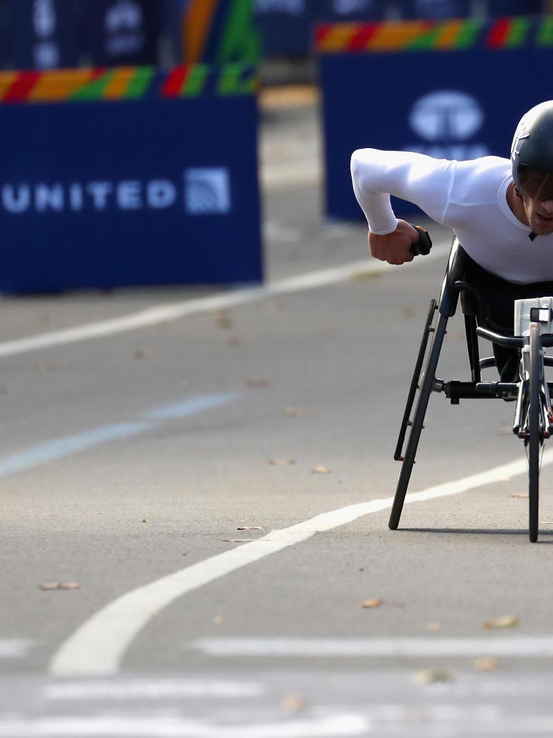 a male wheelchair racer heads towards the finish line
