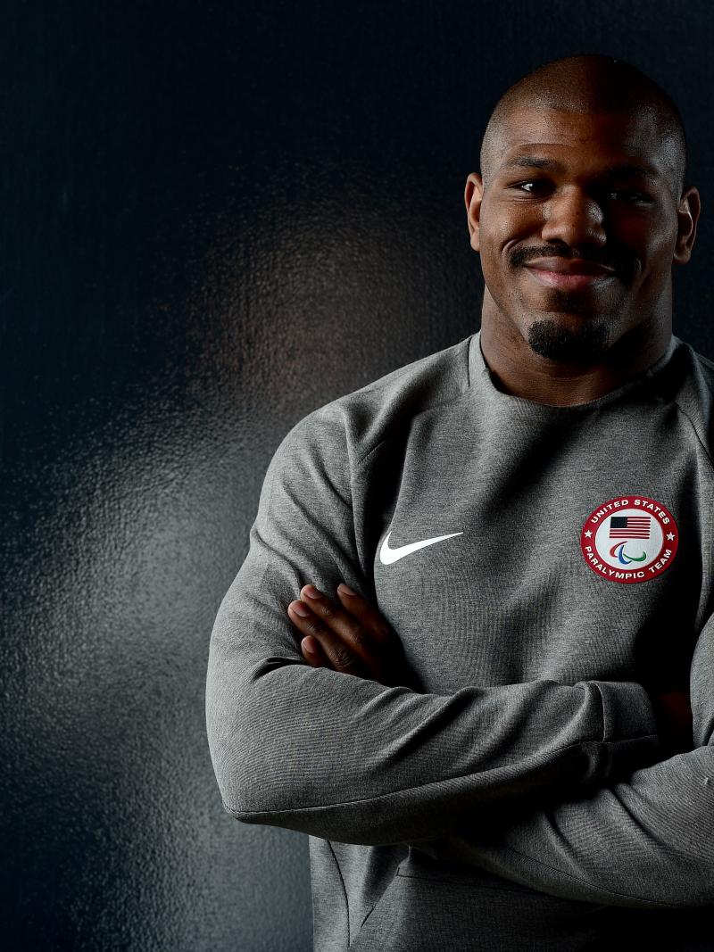 a male judoka smiles with his arms folded