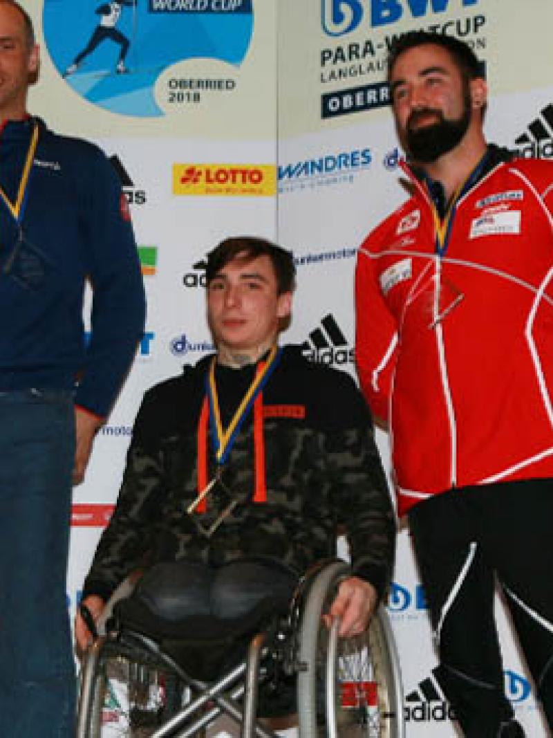 three male sit skiers on the podium