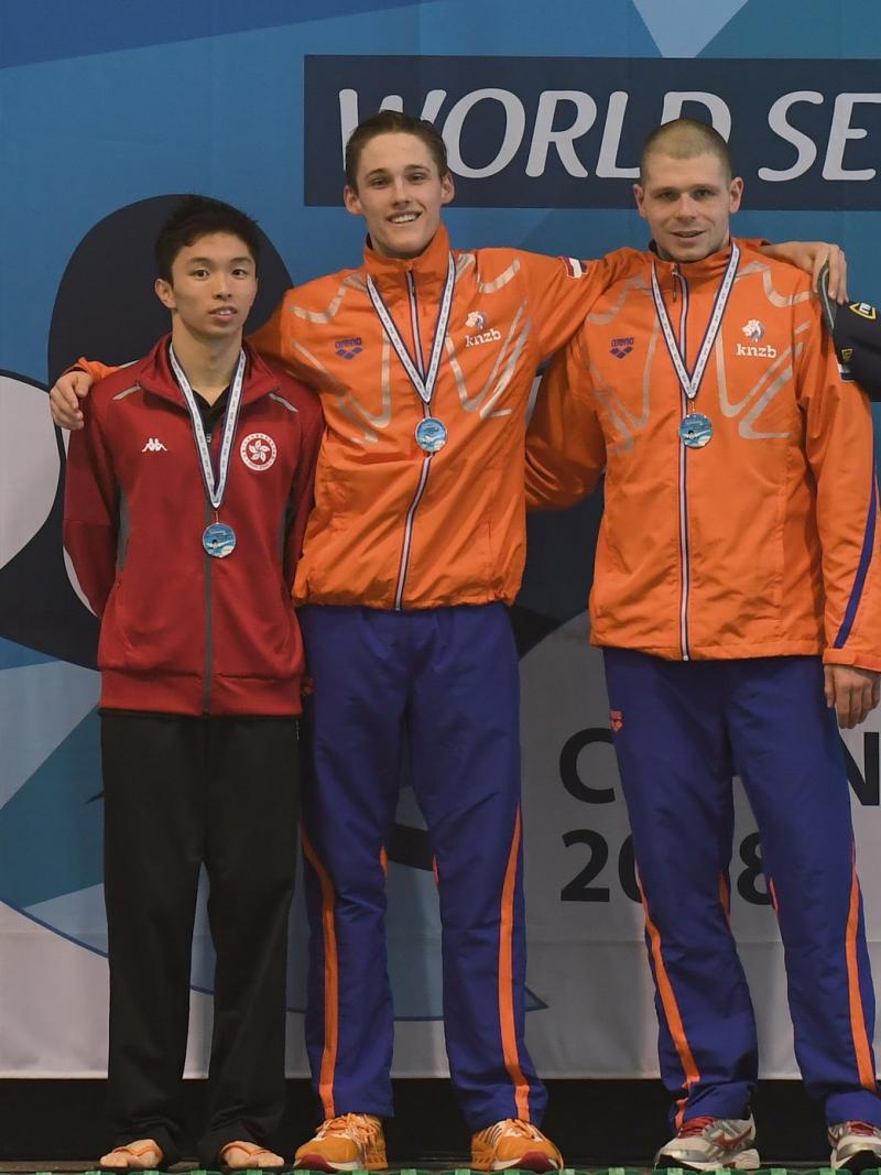 three male swimmers link arms on the podium