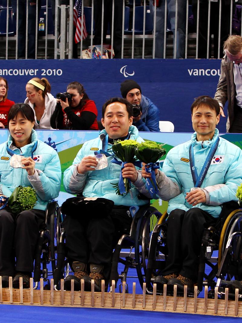 a group of wheelchair curlers celebrate on the podium