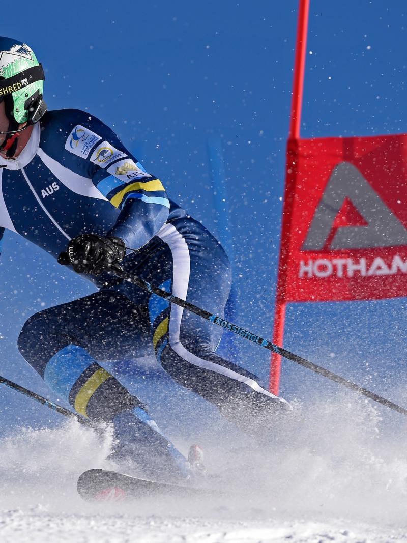 a male vision impaired skier rounds a gate