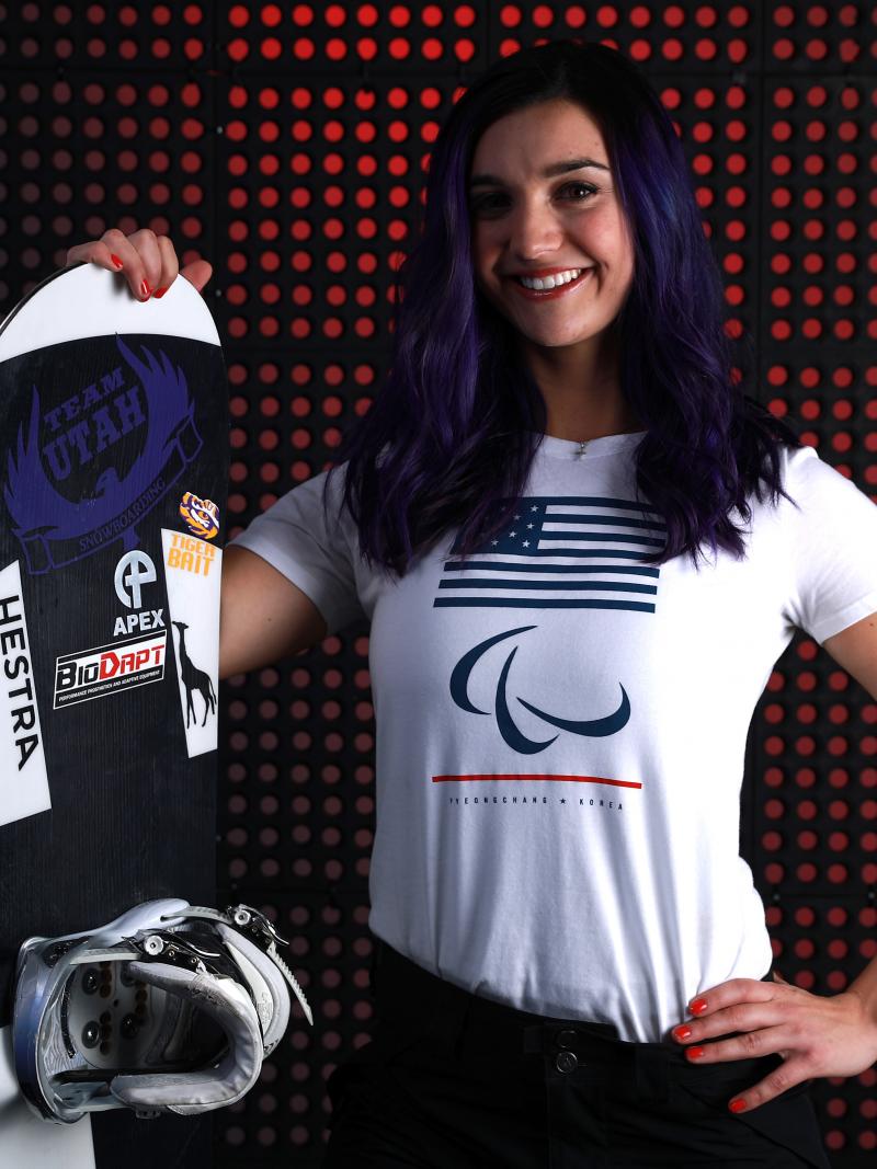 a female Para snowboarder poses with her board