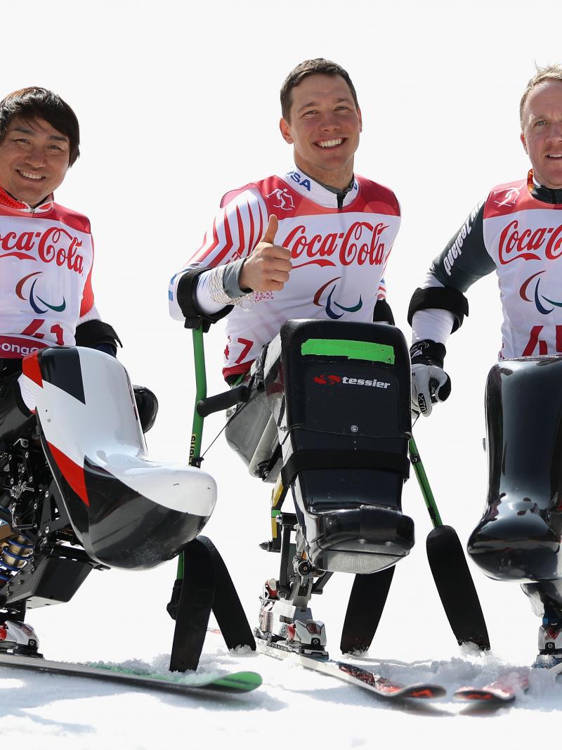 three male sit skiers celebrating on the snow