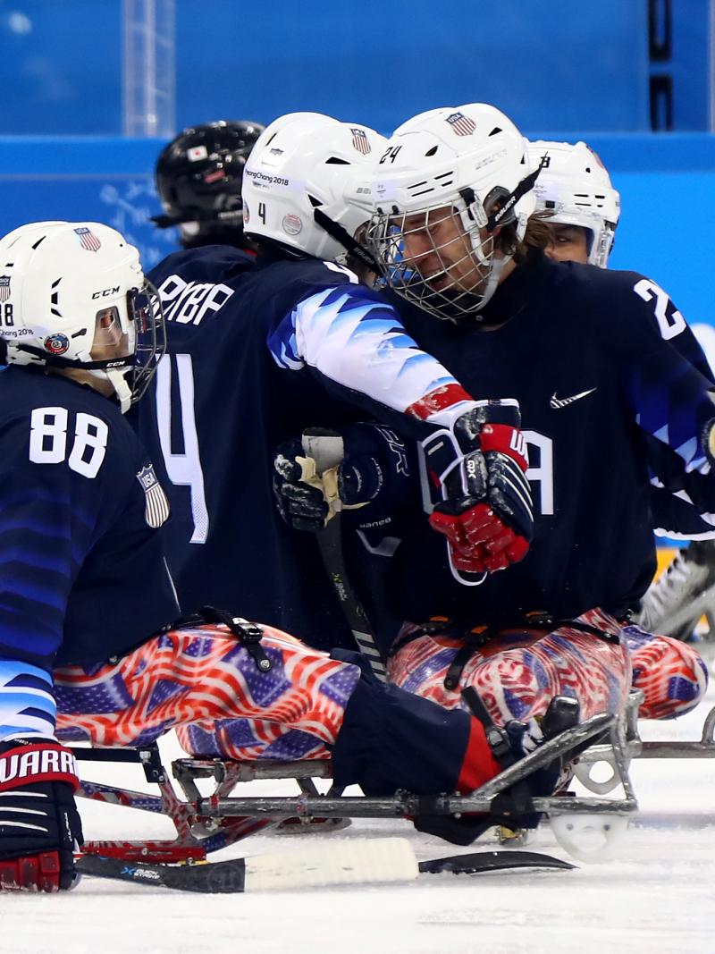 a group of Para ice hockey players celebrating a goal