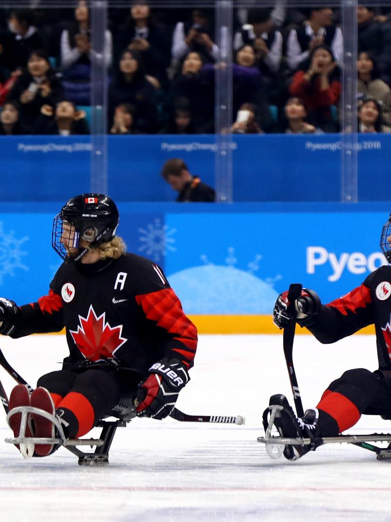 a group of Para ice hockey players celebrate on the ice