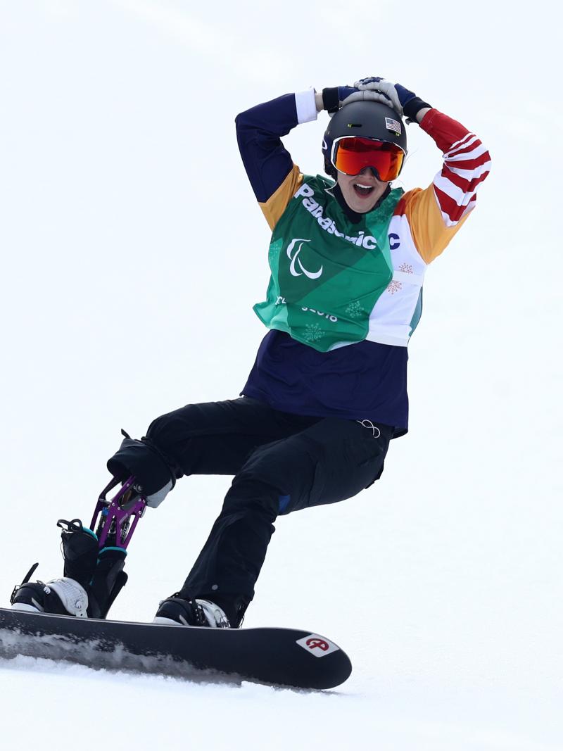 a female Para snowboarder celebrates on the snow