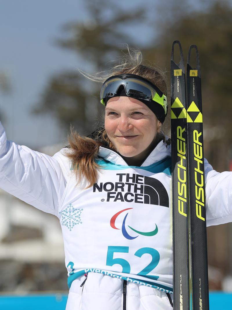 a female Para biathlete celebrates on the podium
