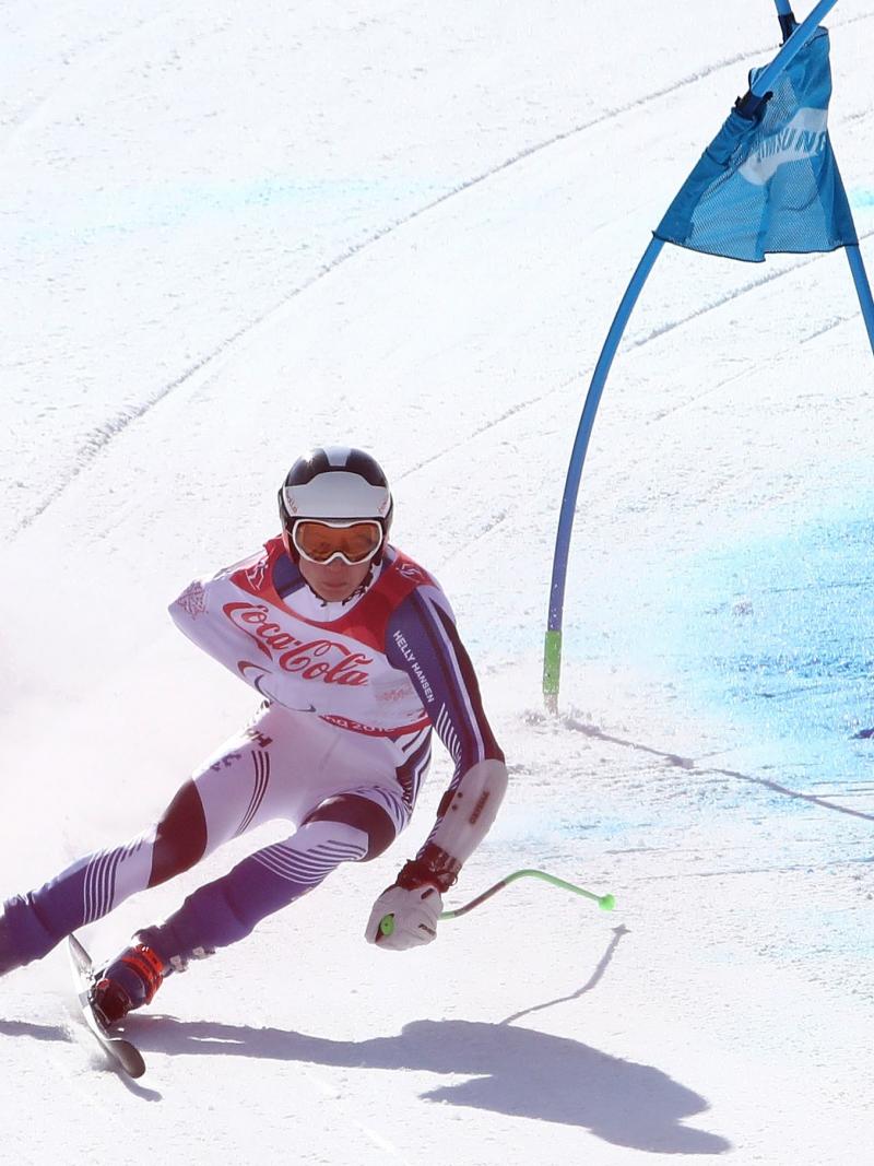 a male Para alpine skier rounds a gate