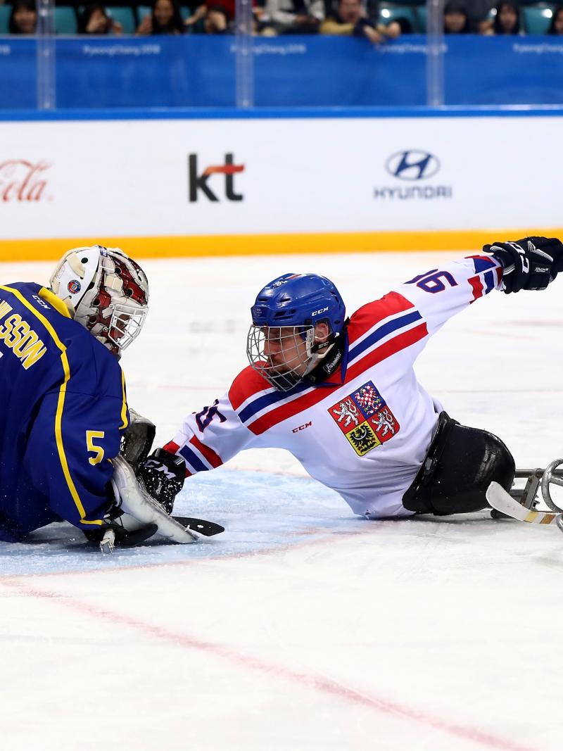 three ice hockey players clash in front of goal