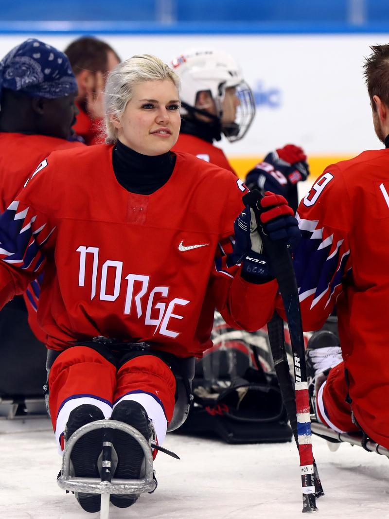 a female Para ice hockey player with her teammates on the ice