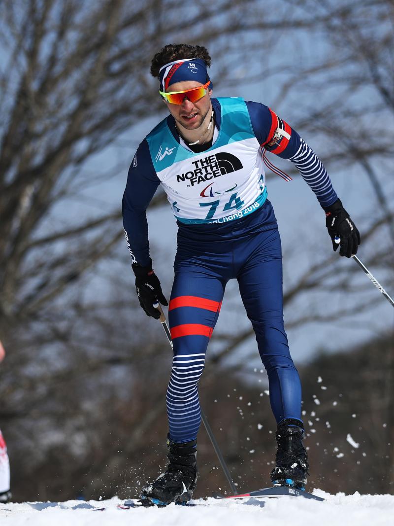 a male biathlete skies through the snow