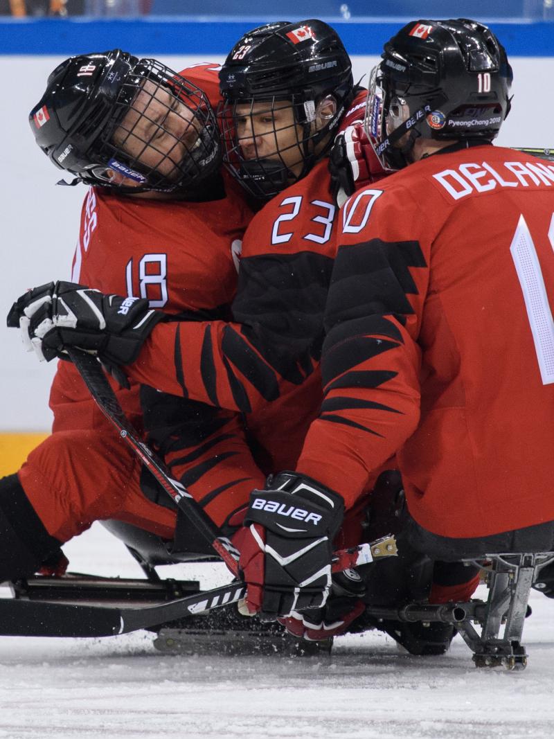 Three Para ice hockey players celebrating a goal
