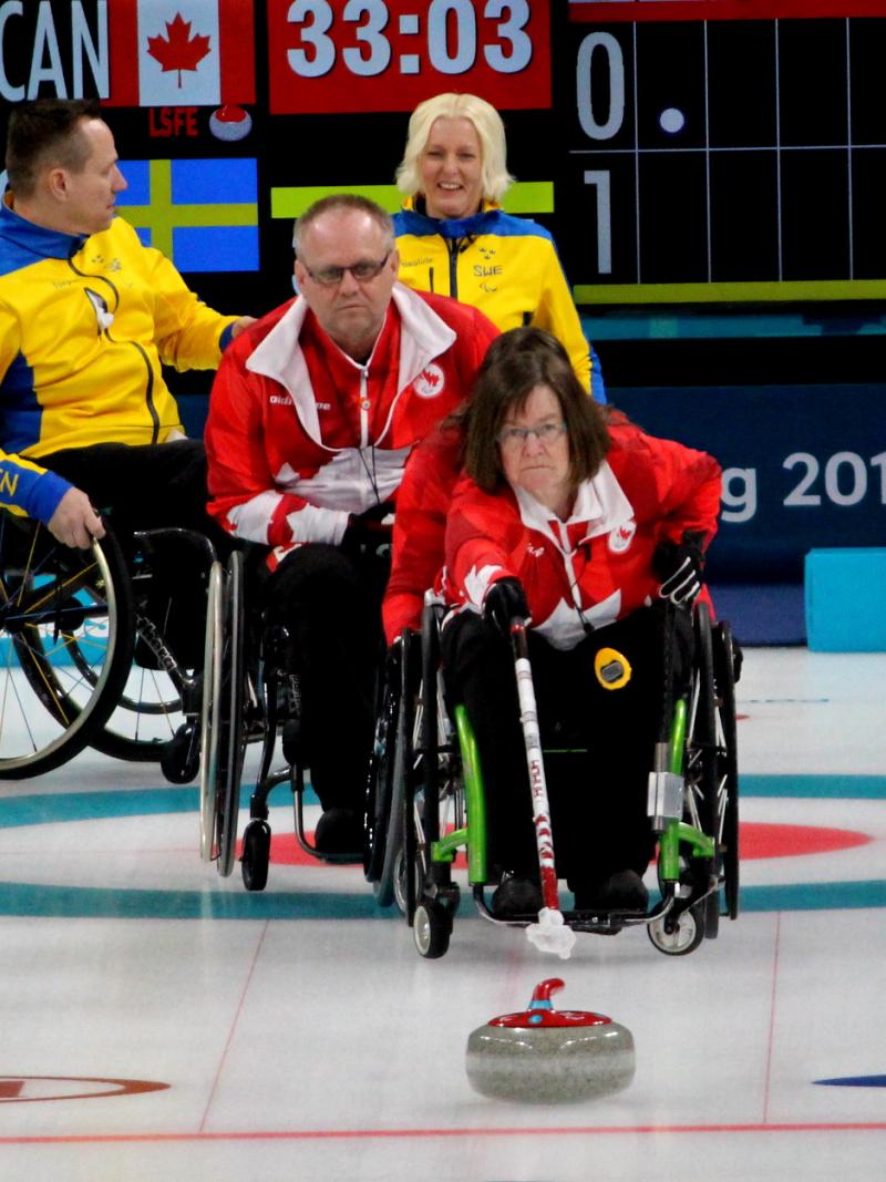 a female wheelchair curler plays a stone