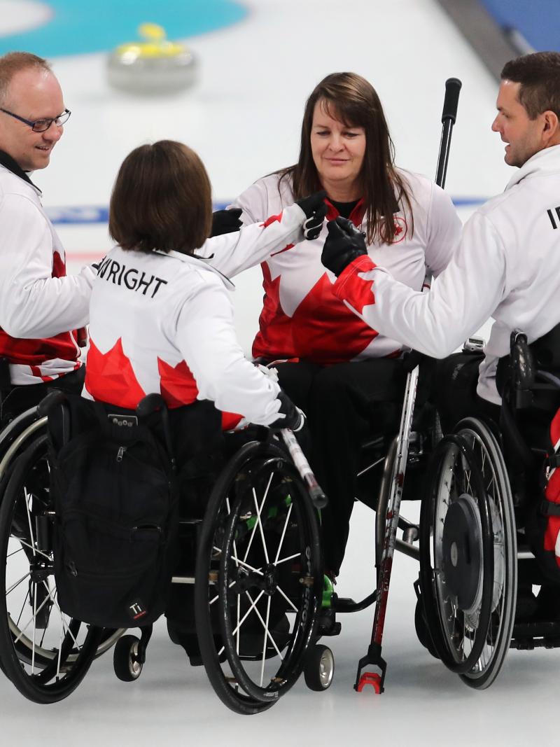 four wheelchair curlers gather in a huddle