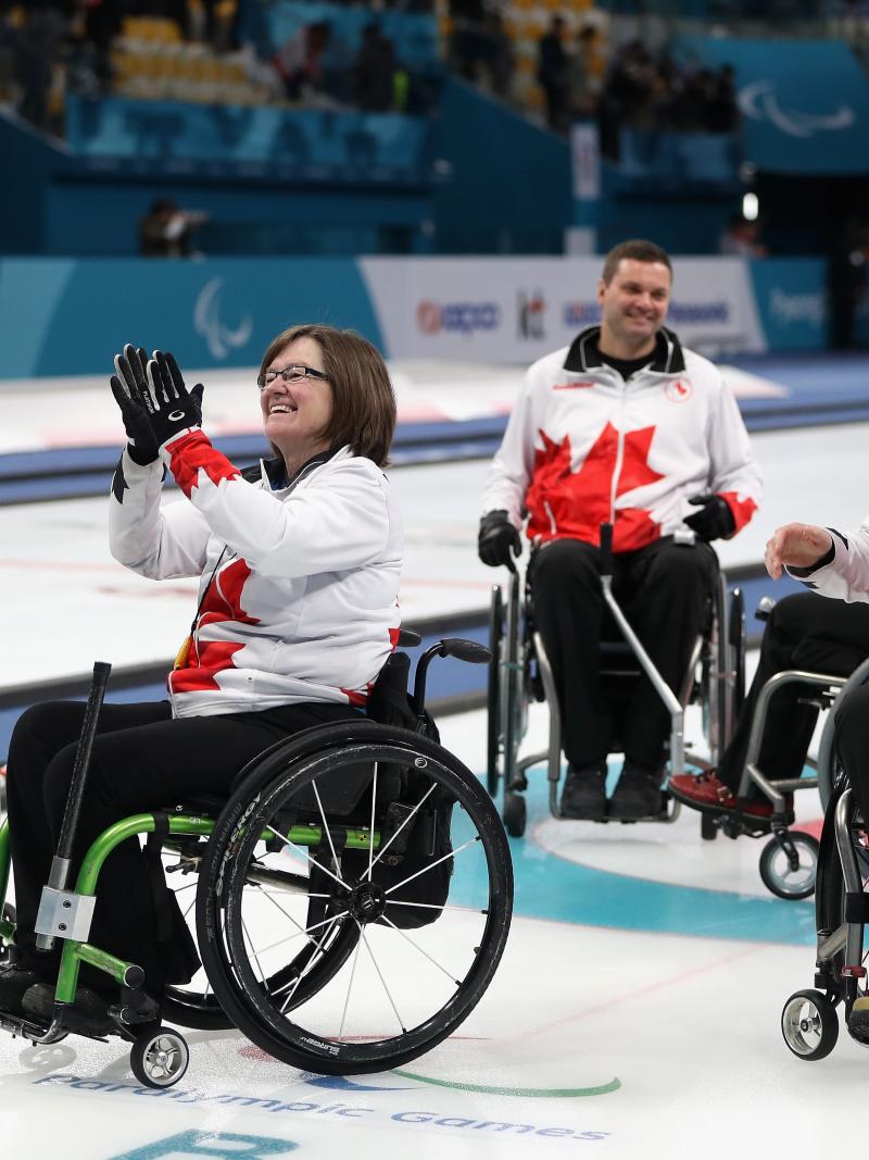 a wheelchair curling team celebrates on the ice