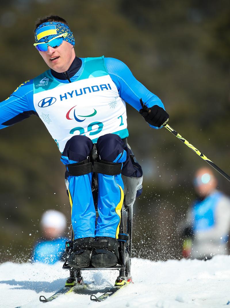a male sit skier ploughs through the snow