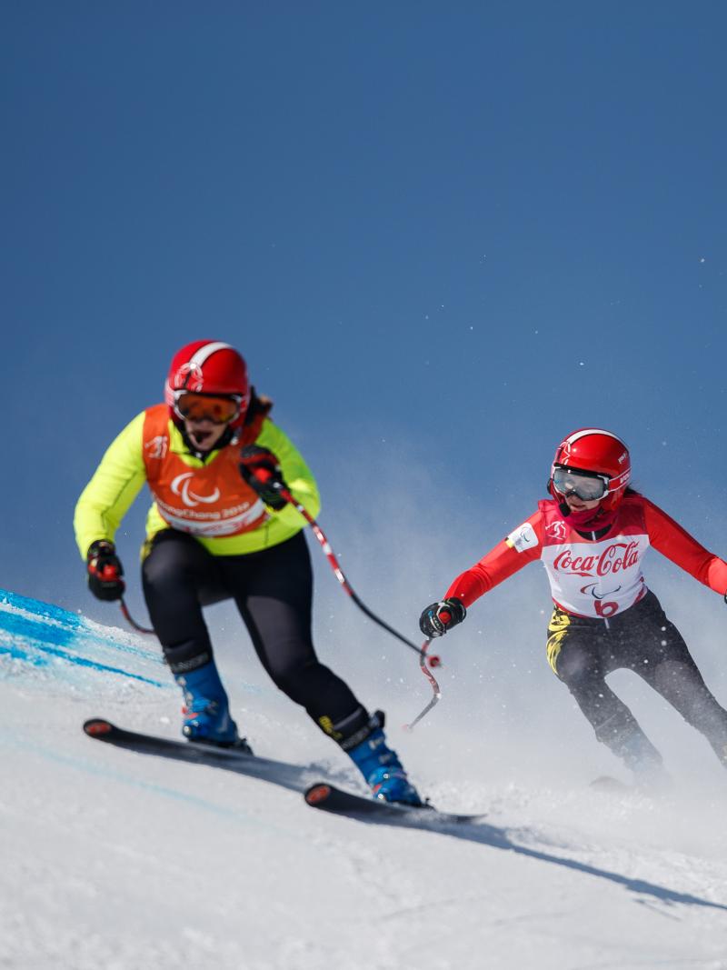 a female vision impaired skier and her guide take on a gate