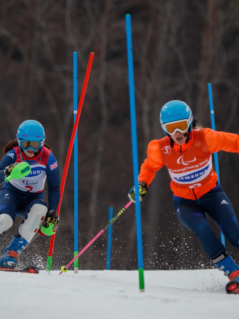 a female vision impaired skier and her guide go through the slalom gates