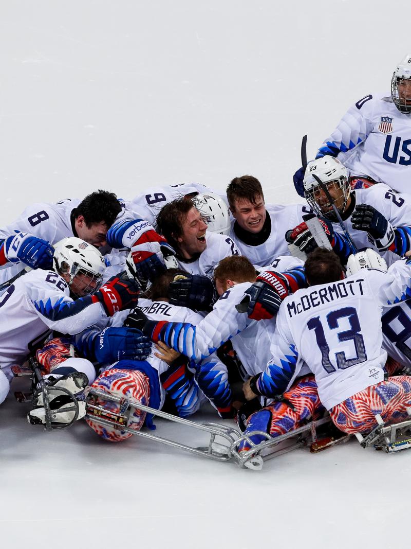 a group of Para ice hockey players celebrate on the ice