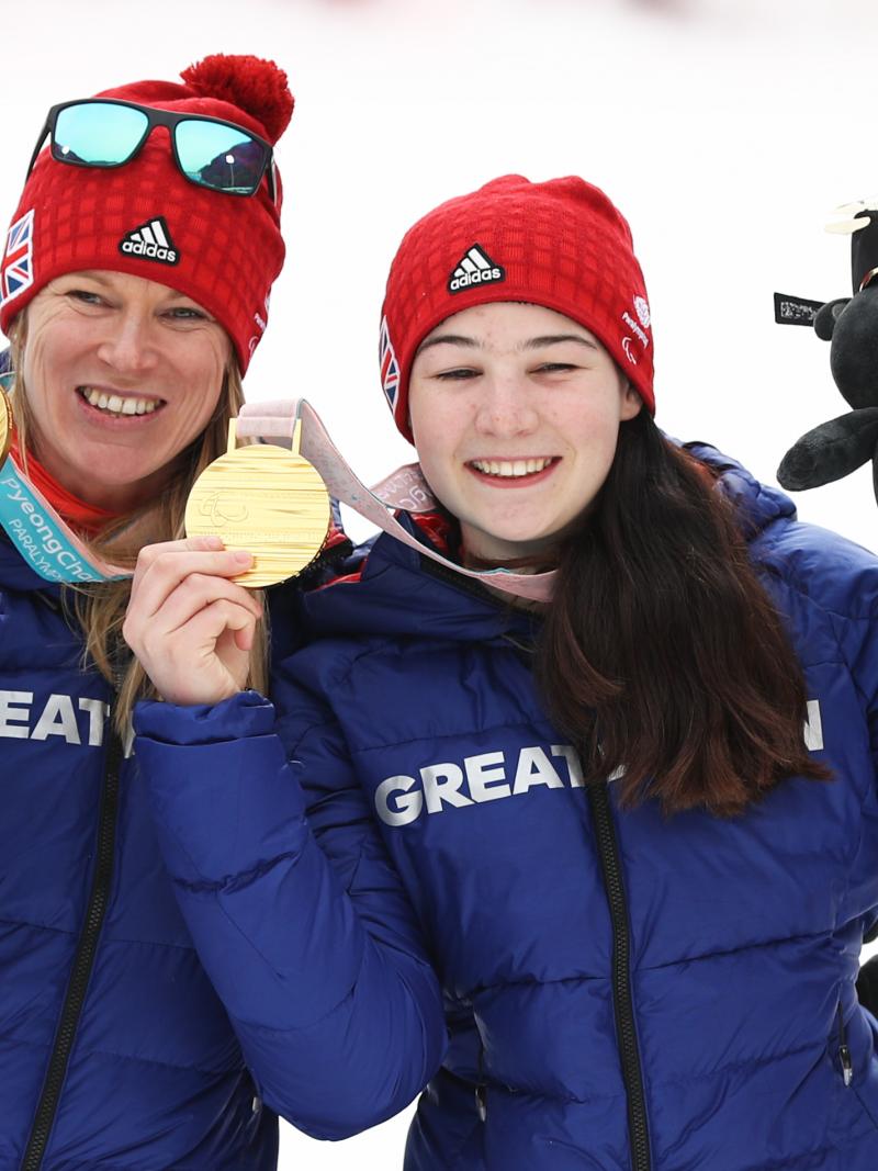two female alpine skiers with gold medals on the podium