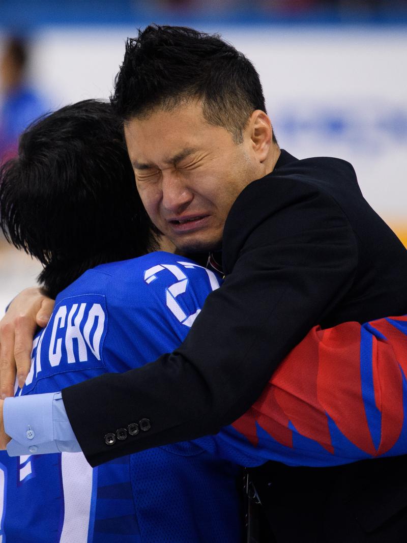 two men embrace and cry on an ice rink