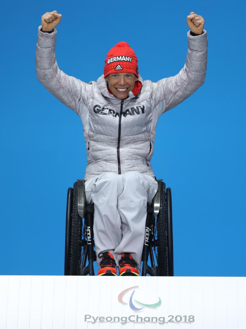 a wheelchair athlete raises her arms on the podium