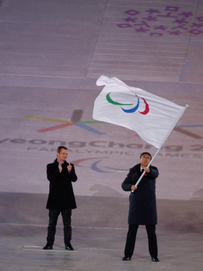 Three men standing, one of them holding a flag