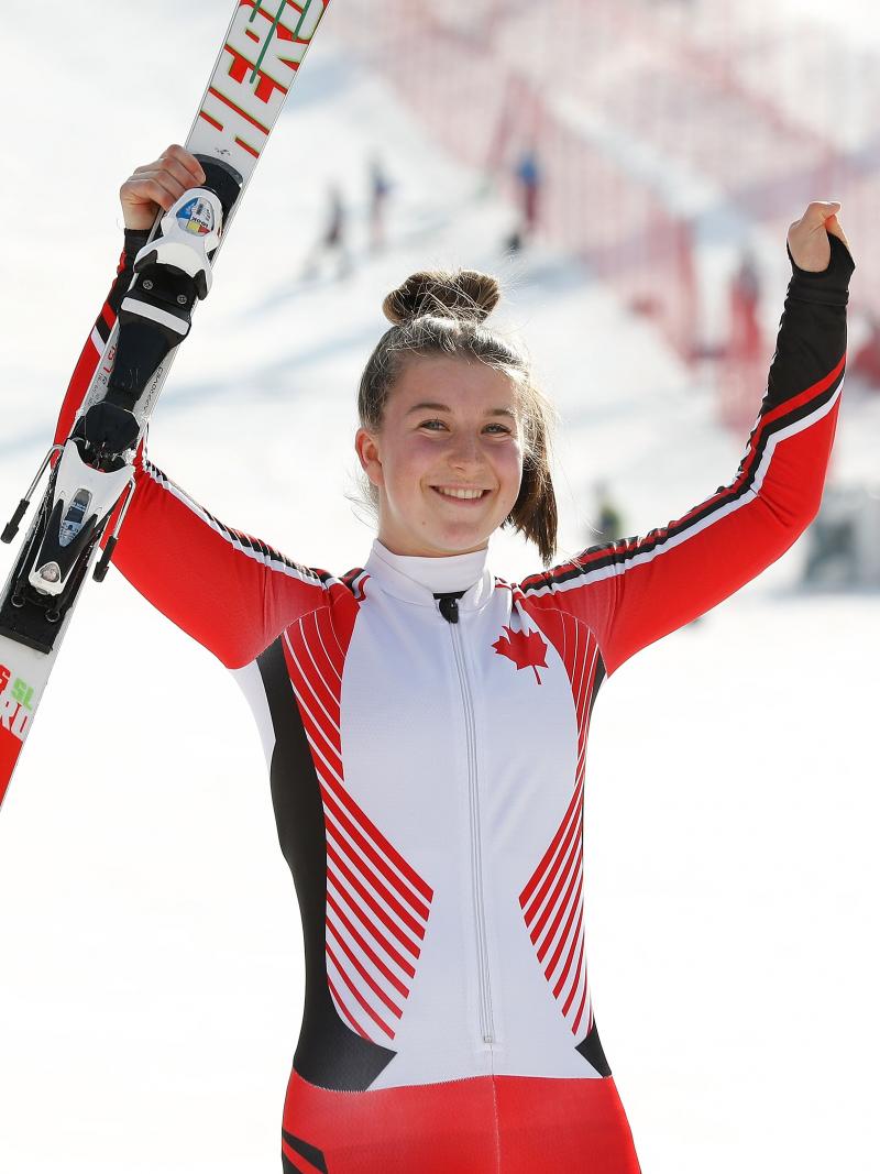a female Para skier raises her arms in celebration